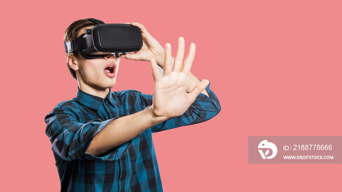 Young man with vr headset on pink background.