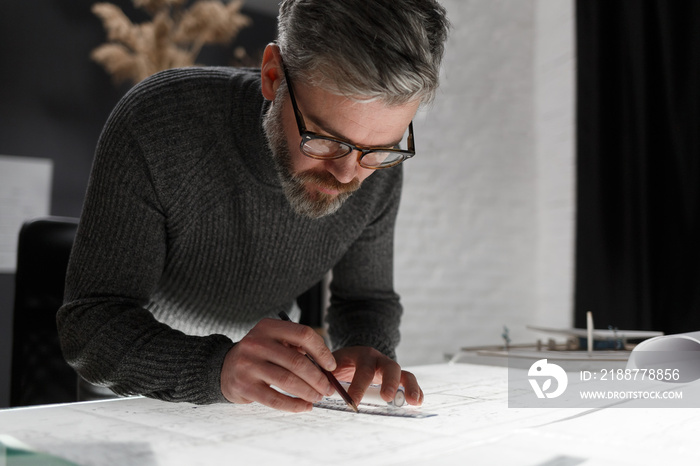 Architect drawing blueprints in office. Engineer sketching a construction project. Architectural plan. Close-up portrait of handsome bearded man concentrated on work. Business construction concept.