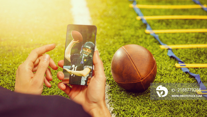 Man use mobile phone, blur image of football match as background.