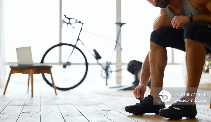 Young man putting on sports shoes at home