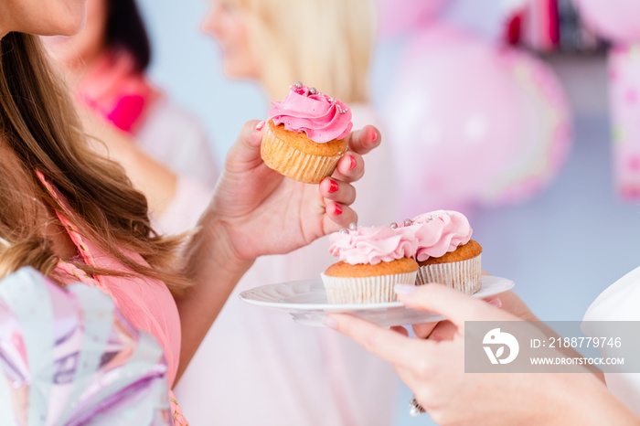 Expecting mother eating pink cupcake on baby shower party