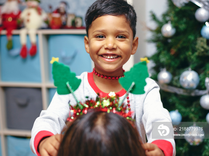 Boy putting Christmas headband on mother