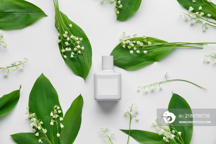 Bottle of perfume and lily-of-the-valley flowers on white background