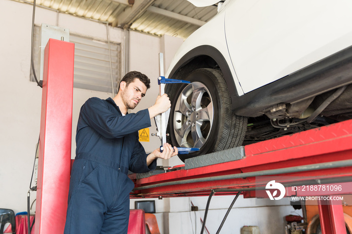 Automobile Worker Using Camber Caster Adapter On Tire