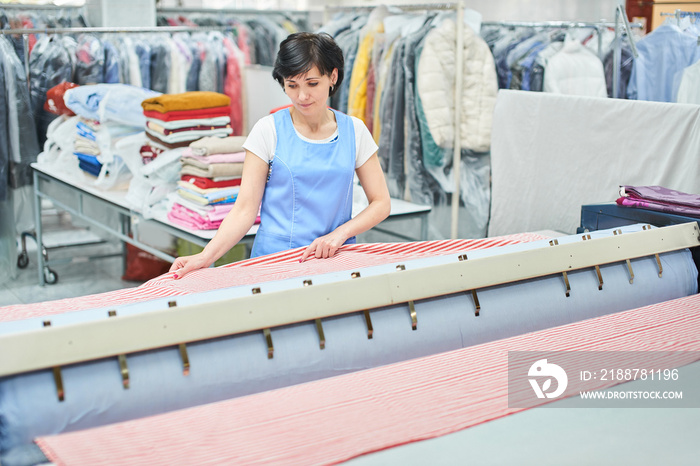 Woman Laundry worker pats the linen on the automatic machine at the dry cleaners