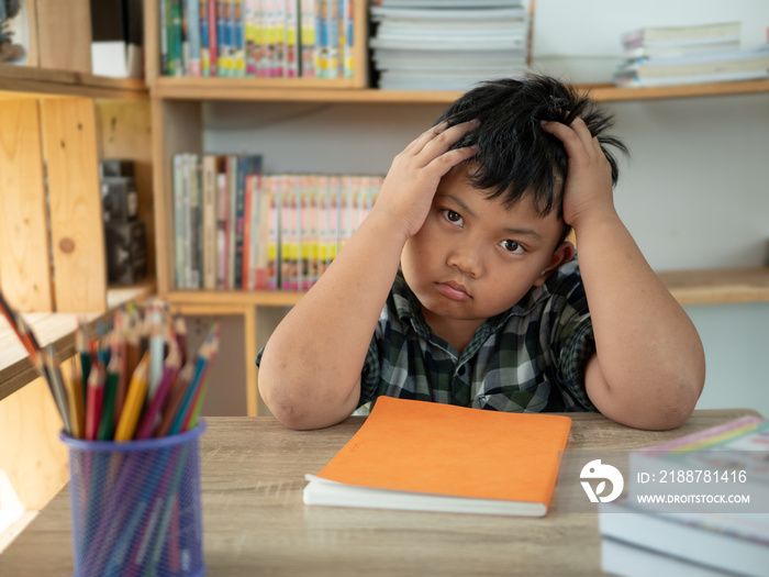 Cute asian children is bored and tired with doing homework on desk in the room. education concept.