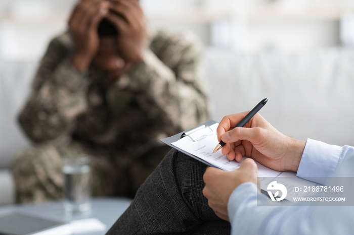 Unhappy black soldier attending therapy session with psychiatrist