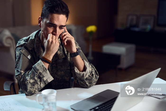 Young sad army soldier talking to someone over mobile phone.