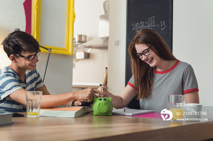 Teenagers saving money in piggy bank.