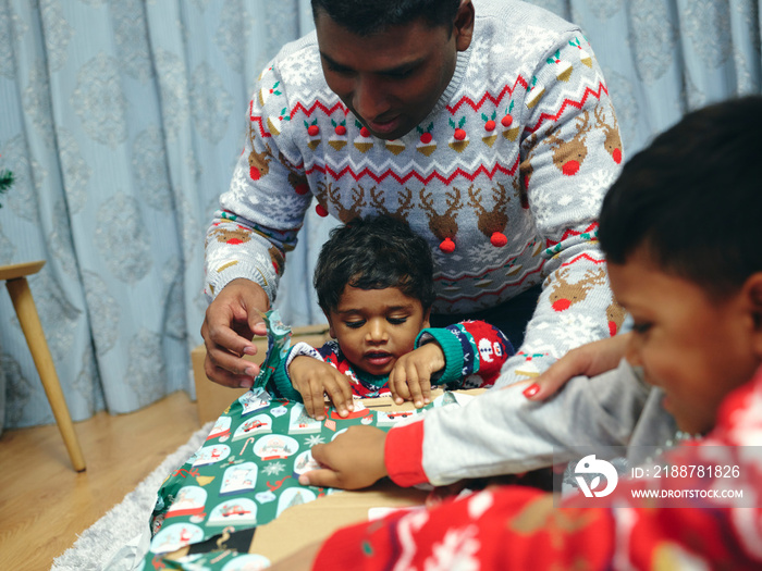 Family with sons opening Christmas presents