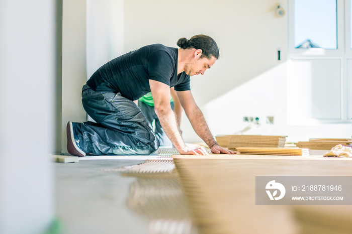 Carpenter on work putting wood parquet pieces. Home construction