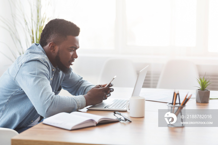 Black office worker using smartphone at workplace