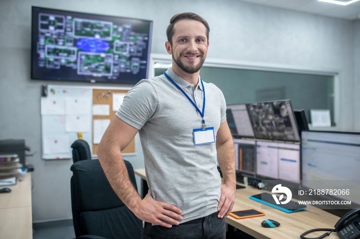 Joyful man standing near work place hands on belt