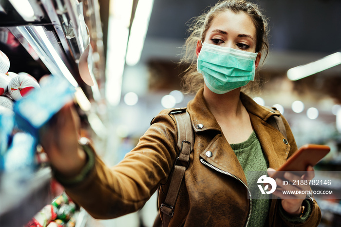 Woman wearing protective mask while using cell phone and buying food in grocery store during virus epidemic.