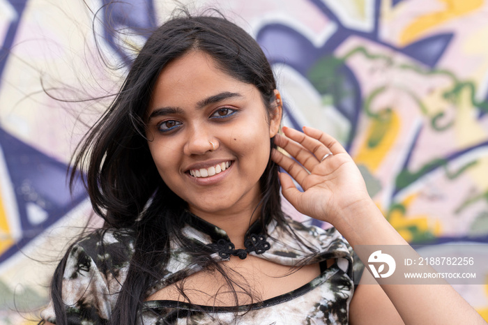 Portrait of young woman against graffiti wall