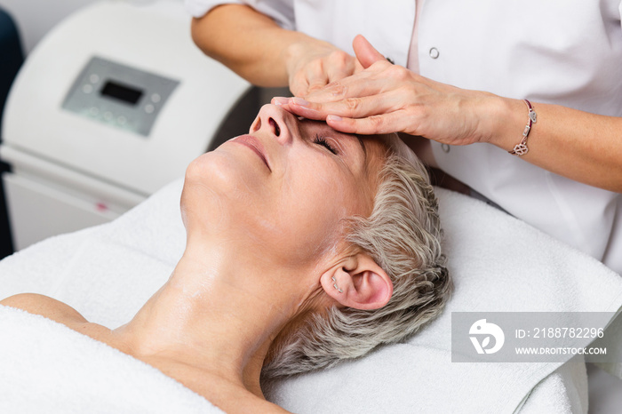 Beautiful senior woman getting spa massage treatment at beauty spa salon. Facial beauty treatment.