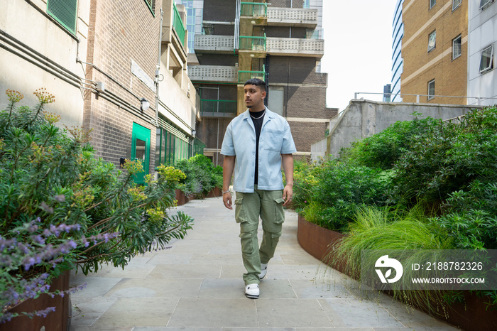 Young man wearing unbuttoned shirt and cargo pants,walking in path