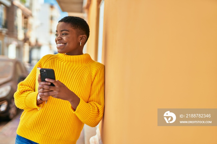 Young african american woman smiling happy using smartphone at the city