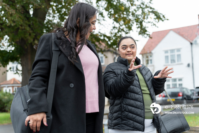 Mother walking with down syndrome daughter in residential district