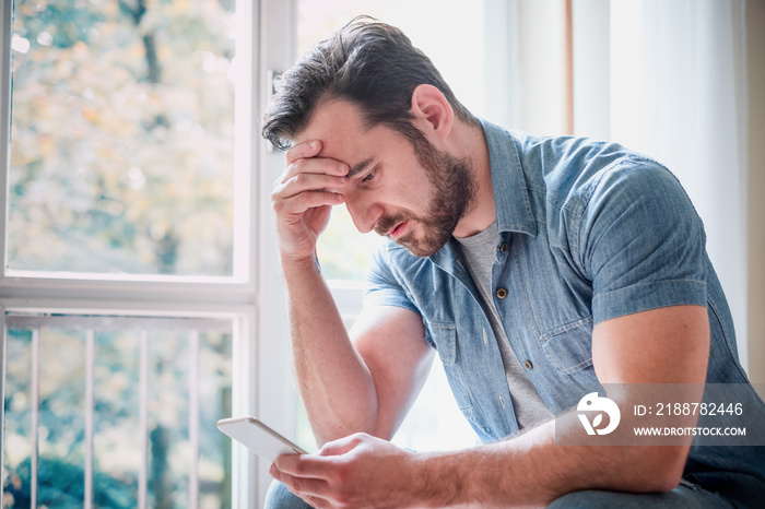 Worried man watching smartphone and waiting message