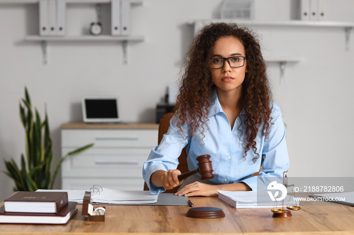 Female judge with gavel at workplace in courtroom