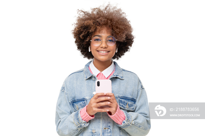 African girl with afro hairstyle and eyeglasses holding phone with both hands, isolated