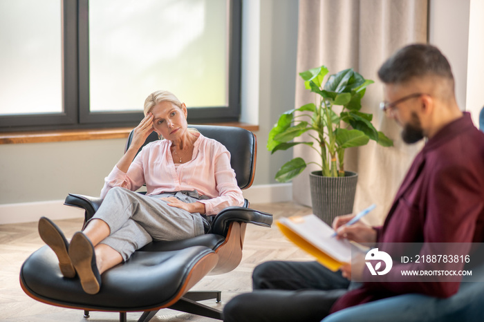 Bearded psychologist wearing glasses listening to mature woman