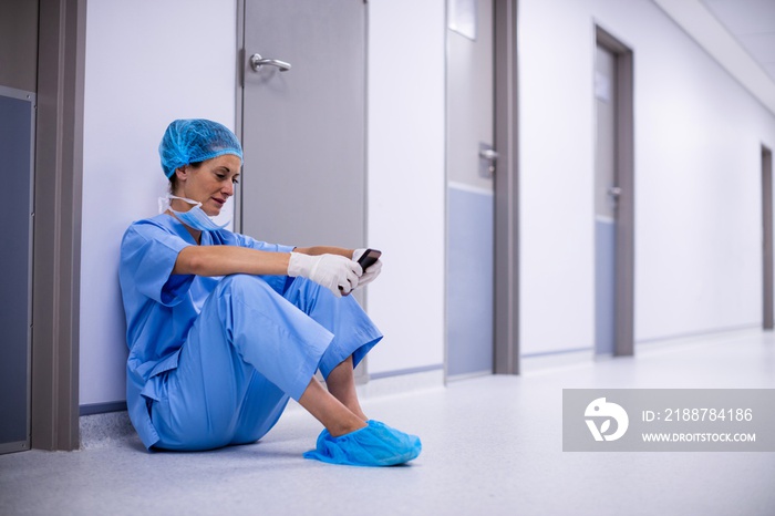 Surgeon sitting on floor and using mobile phone