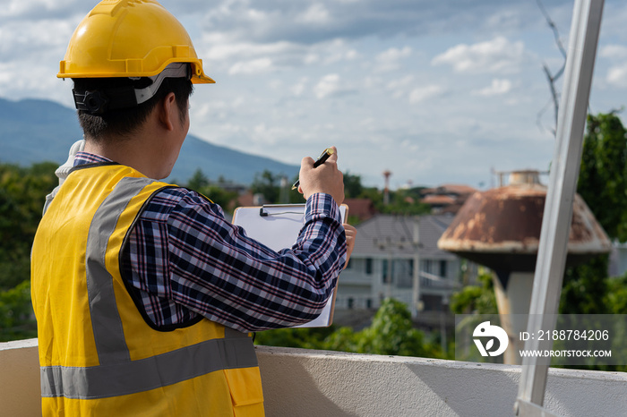 Professional engineers, architects, workers wearing helmets and paperwork in hand with pens at a home construction site.