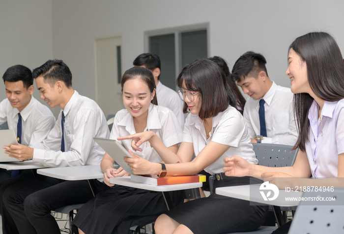 Students in uniform working with tablet in classroom