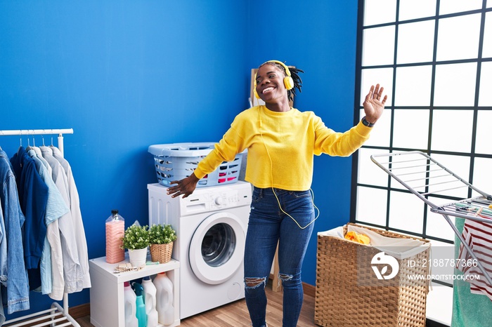 African american woman liatening to music waiting for washing machine at laundry room