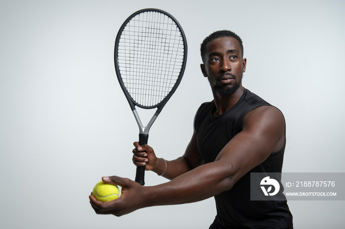 Portrait of man holding tennis ball and racket