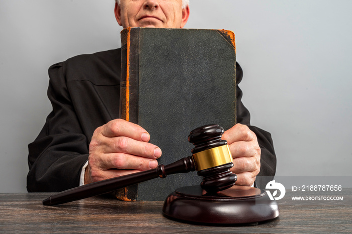 Judge’s gavel on the table in focus. Judge holding a vintage law book. Law Lord wearing gown using a hammer for attention and verdict, justice judgment at courts of law