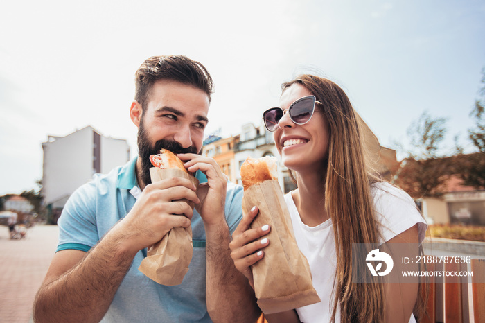 Young couple is eating sandwiches and having a great time