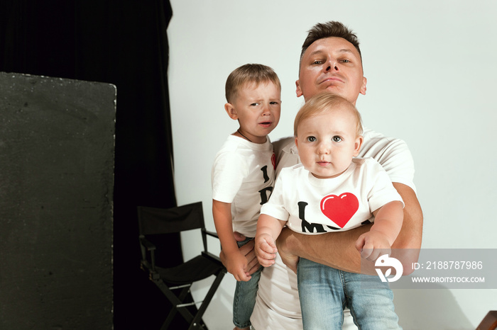 Happy father holding adorable little sons and smiling at camera. Young parent with two childs playing and laughting. Family lifestyle. Father’s day, togetherness, parenthood and kid’s rights concept.