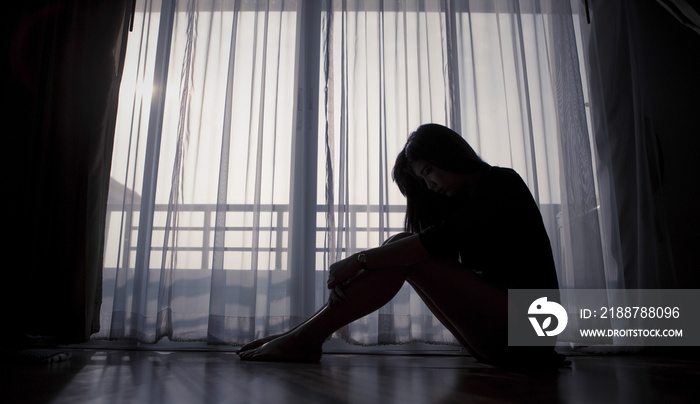 Sad woman sitting alone near window