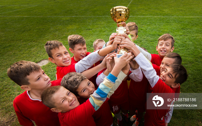 Kids soccer football -  children players celebrating with a trophy after match on soccer field
