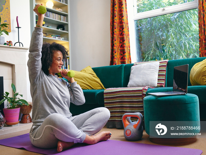 Woman lifting dumbbells at home