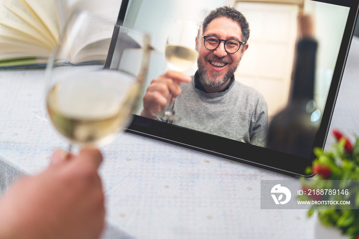 Friends toasting and enjoying drinks online during a video call - Celebrating and connecting virtually in the new normal