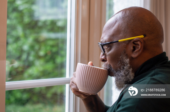 Mature man looking out living room window