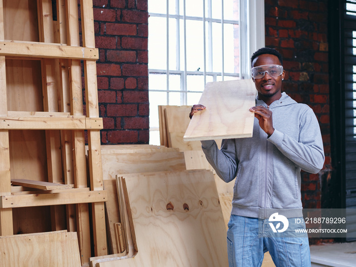 Portrait of carpenter holding plank