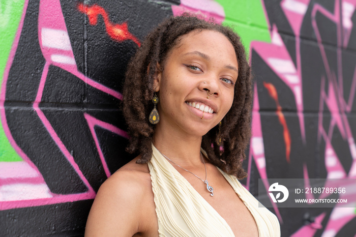 Portrait of smiling woman against graffiti wall