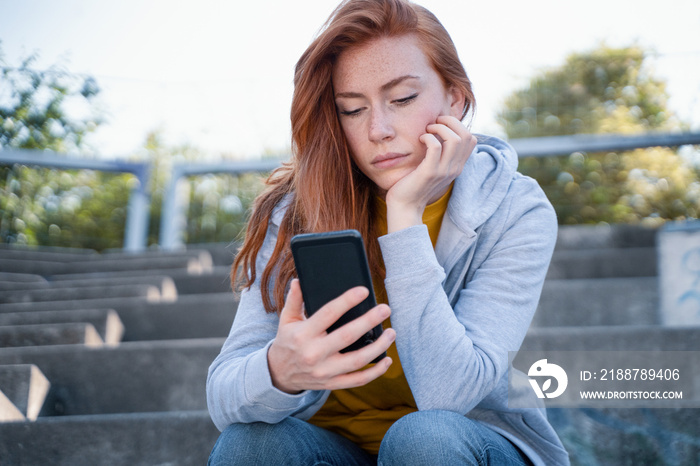 Sad girl watching smartphone and feeling bad