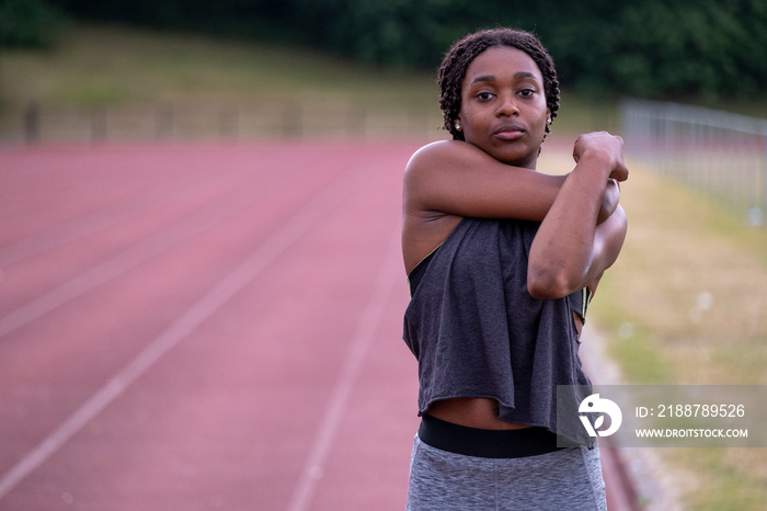 Athletic�woman stretching arm on running track