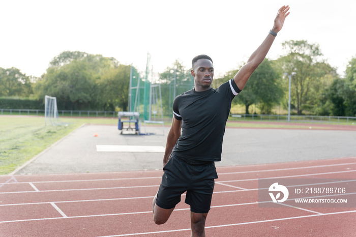 Athlete stretching leg before training at sports track