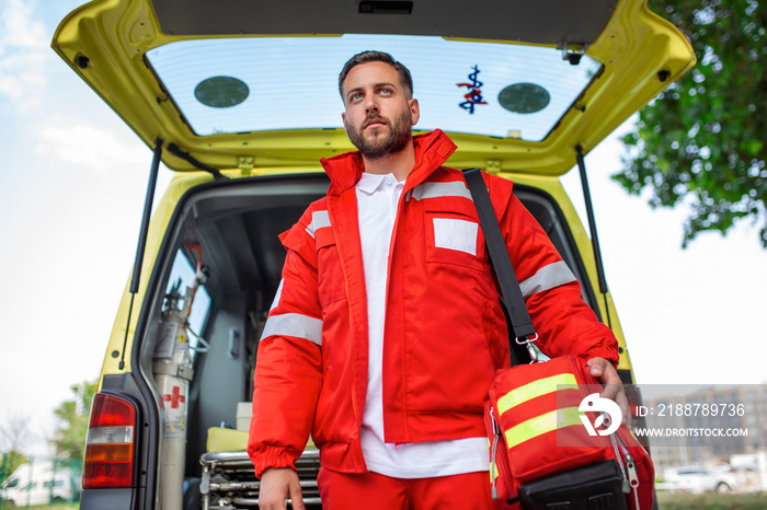 Ambulance staff member emerges from the back of an ambulance with his emergency backpack , and vital signs monitor .