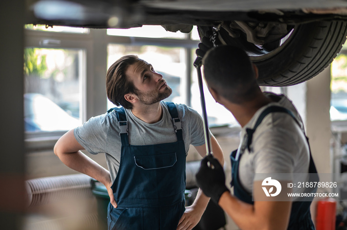 Auto workshop workers providing repair to the client car