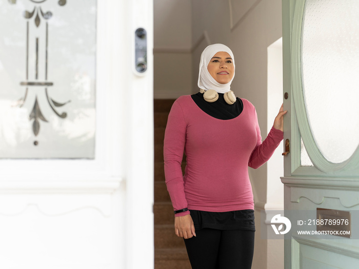 UK,Sutton,Woman in headscarf and sports clothing leaving house