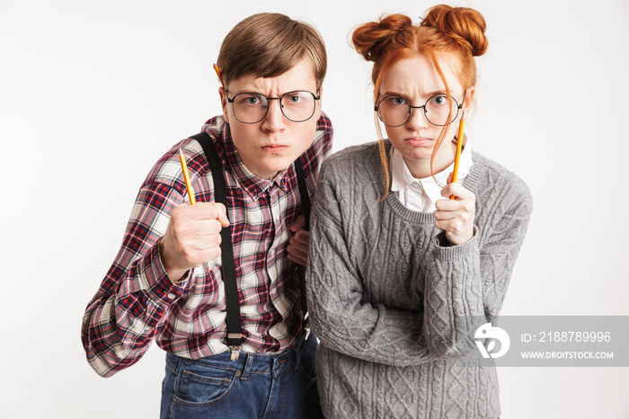 Angry couple of school nerds pointing pencils at camera