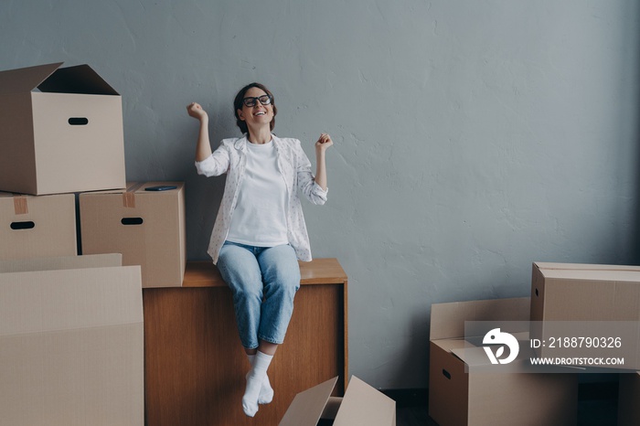 Excited woman doing yes gesture celebrates relocation to new home. Moving day, real estate purchase